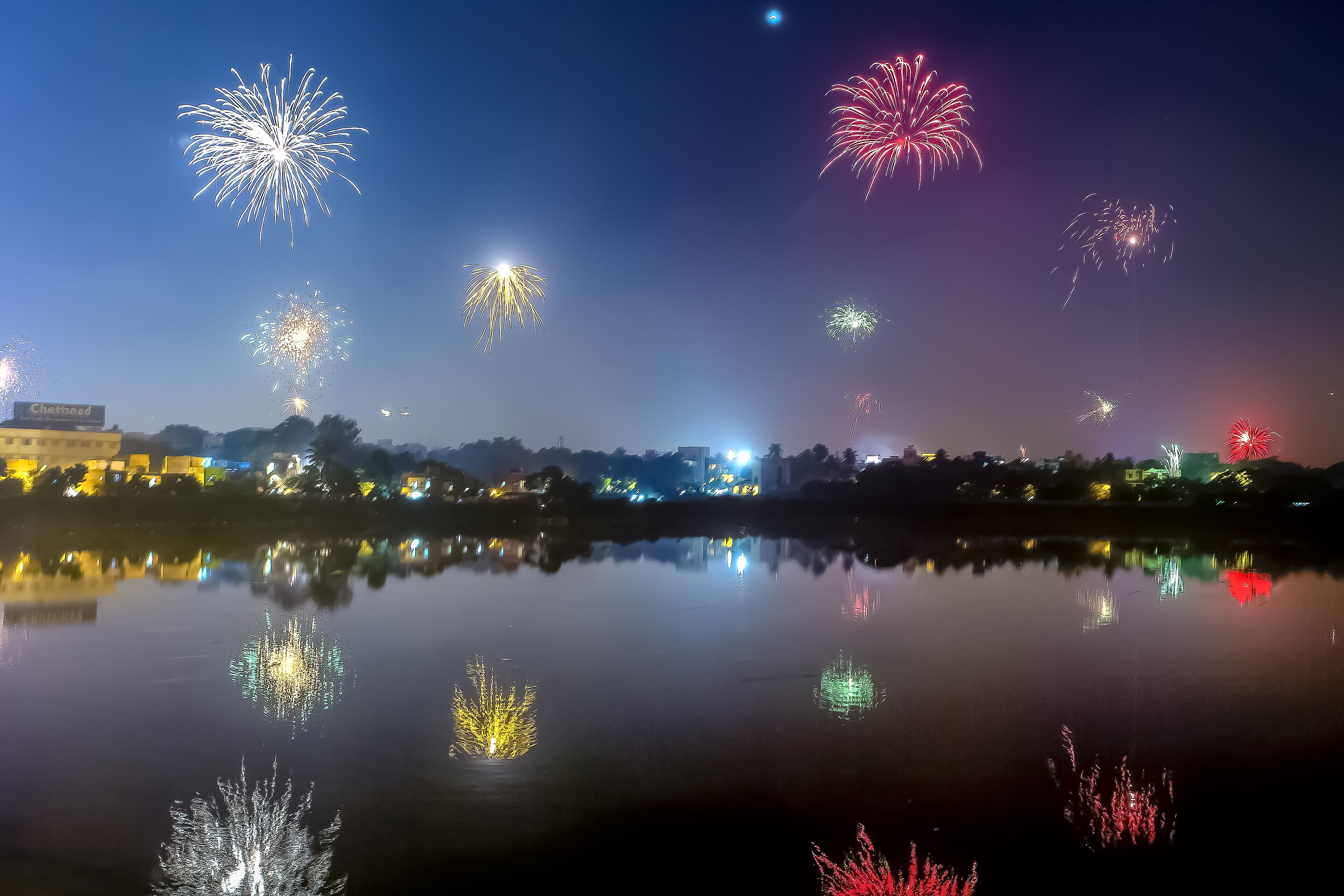 Fireworks bursting over a lake at night